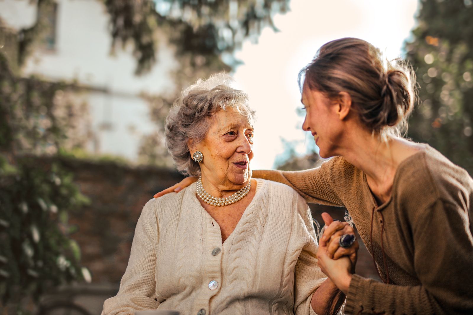 An older woman sharing a warm moment with a companion outdoors